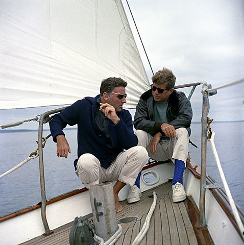 President John F. Kennedy sails with his brother-in-law, Peter Lawford (left), aboard the United States Coast Guard yacht "Manitou" off the coast of Johns Island, Maine. - August 12, 1962