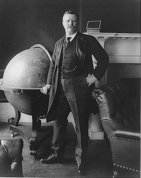 "Theodore Roosevelt, full-length portrait, standing beside large globe, facing front, 1903, in the White House" Copyright: 1903 Photographer: Rockwood Photo Co.